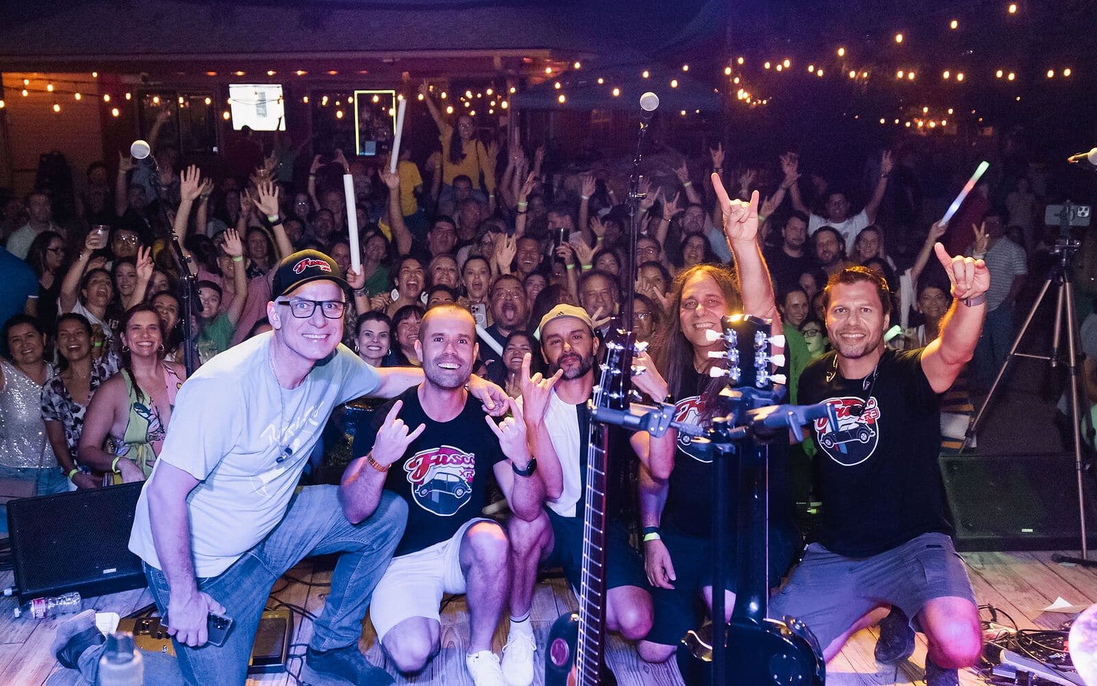 A packed crowd at night with hands in the air